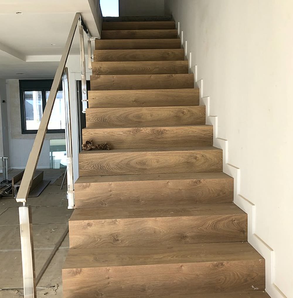 Escalera revestida de roble con barandilla de acero y vidrio